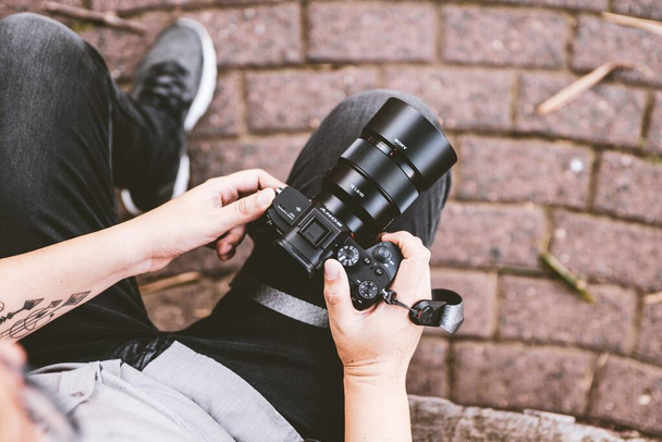 Close up of a person resting while holding a camera with a brick floor background - Фото, зображення