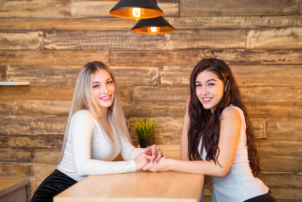 two beautiful young women are sitting at the table - 写真・画像