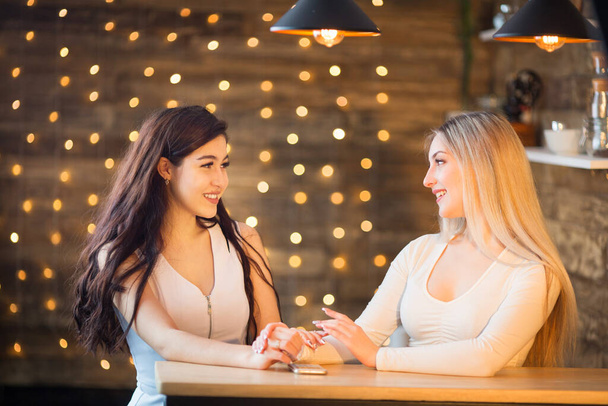 two beautiful young women are sitting at the table - Foto, imagen