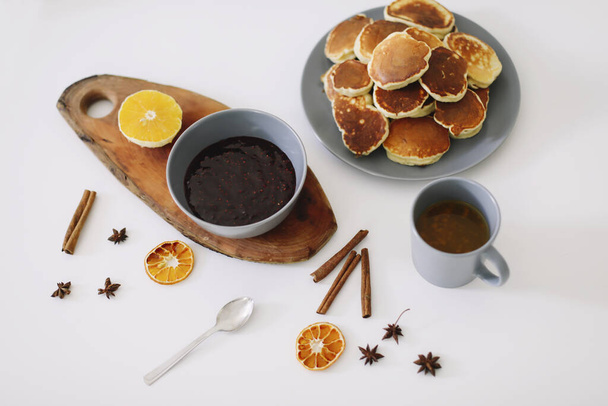 Lush pancakes and teapot with spices, cup of tea with orange, cinnamon, anise. Tasty breakfast on white background. Good morning - Fotó, kép