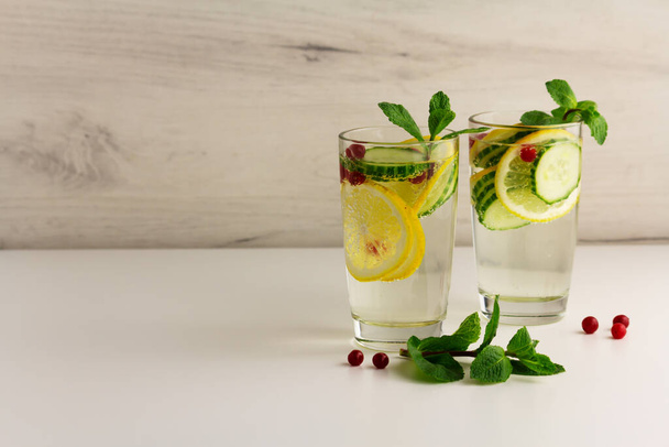 Sassy diet water. Cucumber, lemon, mint lemonade in glasses on light background - Fotoğraf, Görsel