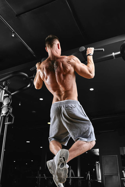 Strong man doing pull-ups on a bar in a gym. - Fotoğraf, Görsel