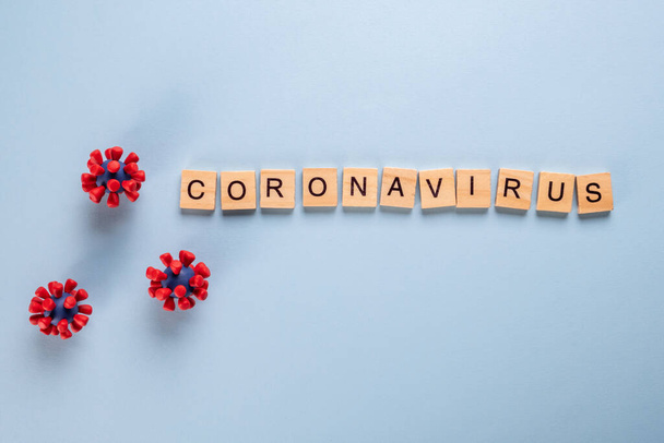 Inscrição coronavírus composto de letras de madeira sobre fundo azul e modelos de covid-19 virus.Virus conceito de proteção pandêmica
 - Foto, Imagem