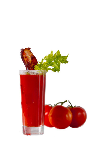 Versare il classico cocktail "Bloody Mary" di vodka, succo di pomodoro e spezie con sedano e pancetta fritta in un bicchiere alto
. - Foto, immagini