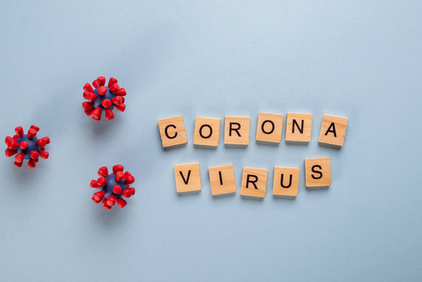 Inscription coronavirus composé de lettres en bois sur fond bleu et de modèles de virus covid-19.
 - Photo, image