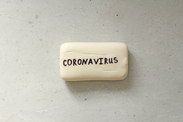 White soap lies on light gray background, word coronavirus is written on soap. Concept of hand washing, hygiene, for prevention of coronavirus, other viruses, to stop spread coronavirus covid 2019. - Foto, Imagen