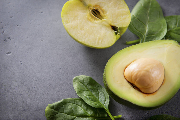 avocado halves with a stone, Apple, fresh green spinach leaves on a gray background, copy space,  close up - Foto, Imagem