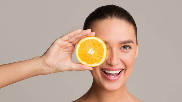 Frutas e conceito de cuidados com a pele. Mulher segurando pedaço de laranja
 - Foto, Imagem