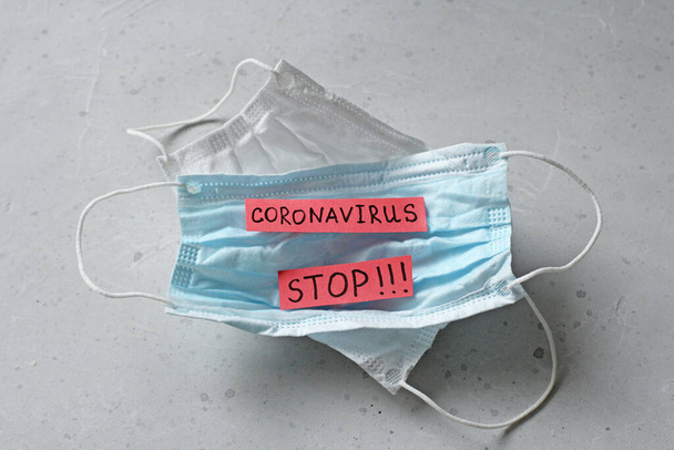 Coronavirus kelimesinin yazıldığı iki tıbbi maske. Kauçuk kulaklıklı cerrahi maske. Tipik 3 katlı cerrahi maske ağız, burun. Prosedür maske bakterisi. Koronavirüse karşı koruma. - Fotoğraf, Görsel