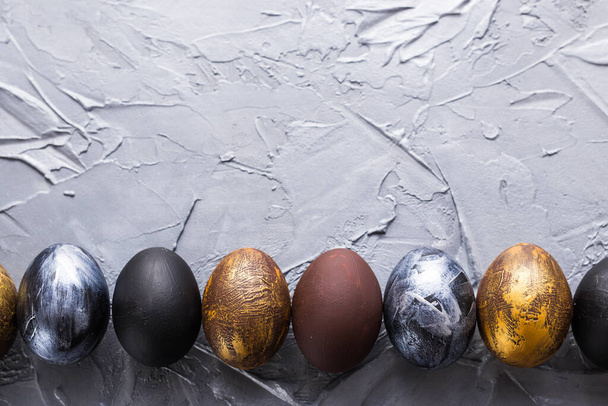 Férias, tradições e conceito de Páscoa - Ovos de páscoa de estilo escuro em fundo cinza com copyspace
. - Foto, Imagem