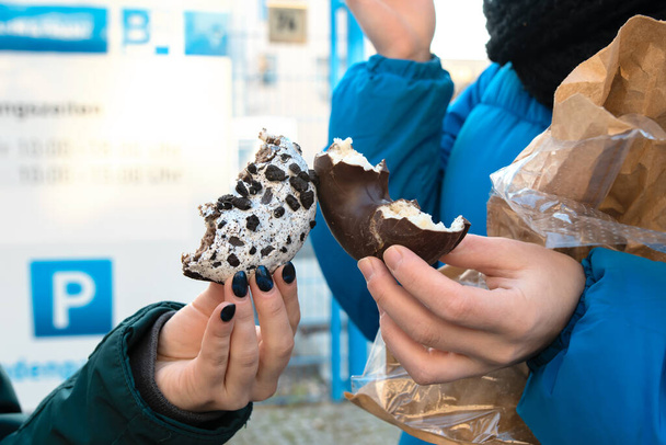 Female hands with tasty choco doughnut in the real life outdoor - Photo, Image