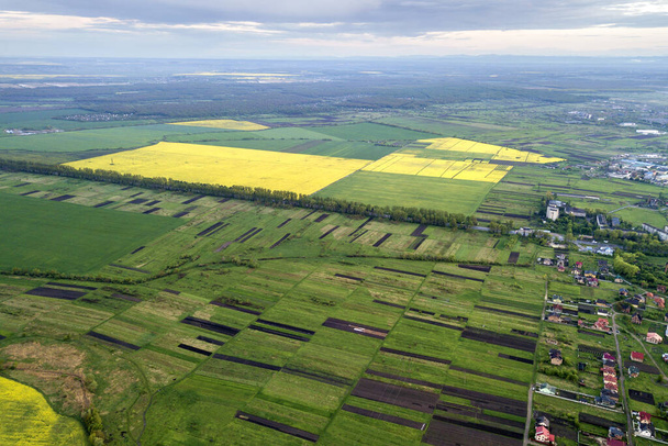 Paysage rural au printemps ou en été. Vue aérienne des champs verdoyants, labourés et fleuris, des toits des maisons à l'aube ensoleillée. Photographie de drone. - Photo, image