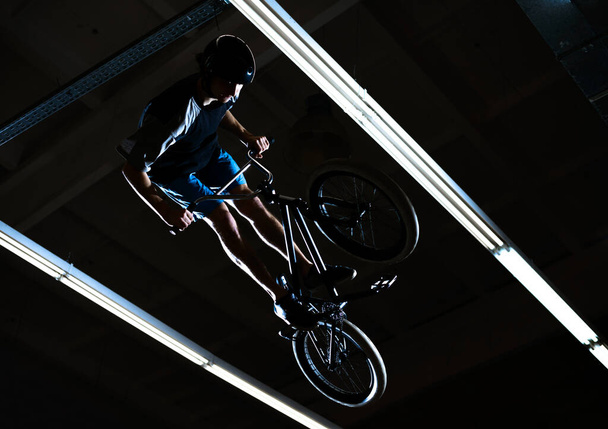 BMX Rider Doing Extreme Tricks on Bike in the Dark Skatepark. Healthy and Active Lifestyle. - Zdjęcie, obraz