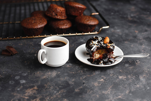 Chocolate cupcakes, muffins with banana, nuts and a Cup of coffee. On a black table and a dark background. Top view, side view. Close-up and medium plan. Space for text. - 写真・画像