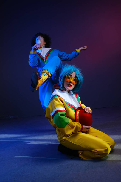 Dois palhaços um homem e uma mulher com maquiagem em trajes coloridos brilhantes no estilo dos anos 80
. - Foto, Imagem