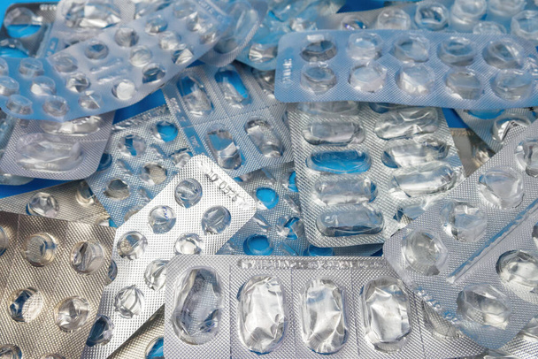 Many used blister packs without pills on blue background. Medical and healthcare concept - Φωτογραφία, εικόνα