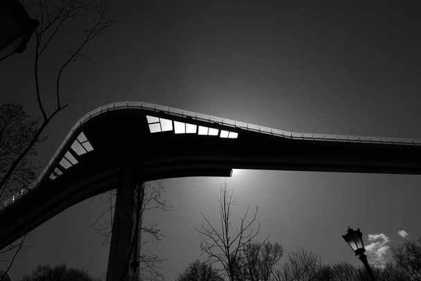 Un grand pont piéton-vélo menant à la partie centrale de la ville, à travers le plancher de verre dont le soleil est visible
.  - Photo, image