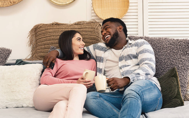 Мужчина и женщина сидят на диване и смеются
 - Фото, изображение