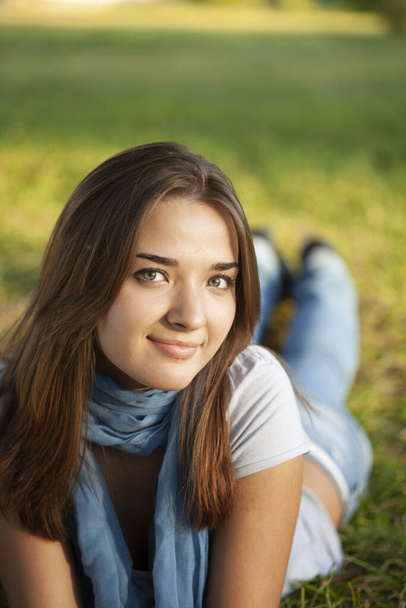 Beautiful girl with long white hair lies on green grass and smiles. - Φωτογραφία, εικόνα