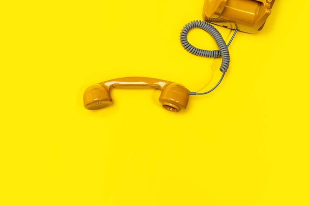 Old fashioned handset on yellow color background. Modern retro style of rotary telephone. - 写真・画像
