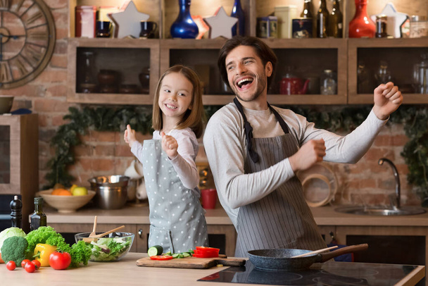 Retrato de alegre menina e seu pai dançando na cozinha
 - Foto, Imagem