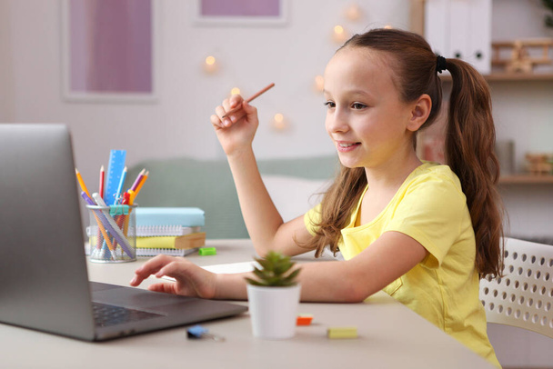 Μικρό χαριτωμένο κορίτσι εργάζεται σε ένα σύγχρονο φορητό υπολογιστή. - Φωτογραφία, εικόνα
