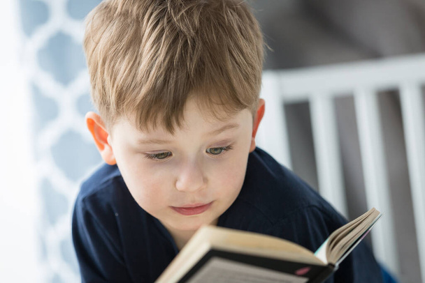 Niño leyendo un libro en casa
 - Foto, Imagen