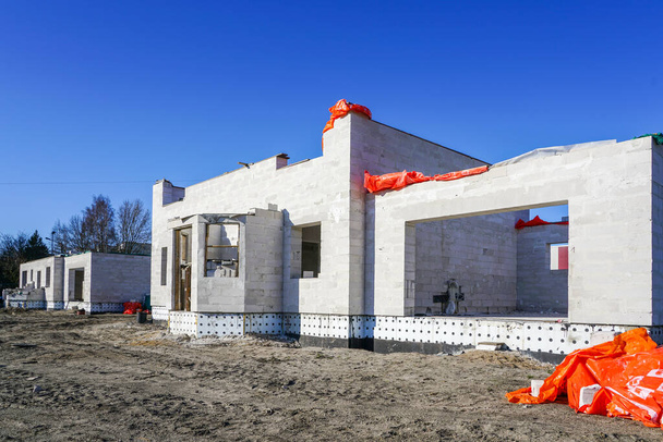 construir una nueva casa utilizando bloques de construcción en blanco sobre un fondo azul del cielo
 - Foto, imagen