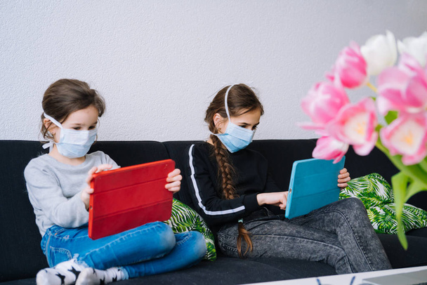 Online-Bildung, Fernunterricht, Hausaufgabenbetreuung. Kinder in medizinischer Maske lernen Hausaufgaben während des Online-Unterrichts zu Hause in digitalem Tablet oder Laptop. Soziale Distanz in Quarantäne. Selbstisolierung - Foto, Bild