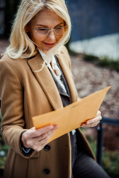 Pleased female entrepreneur holding a document outdoors - Фото, зображення