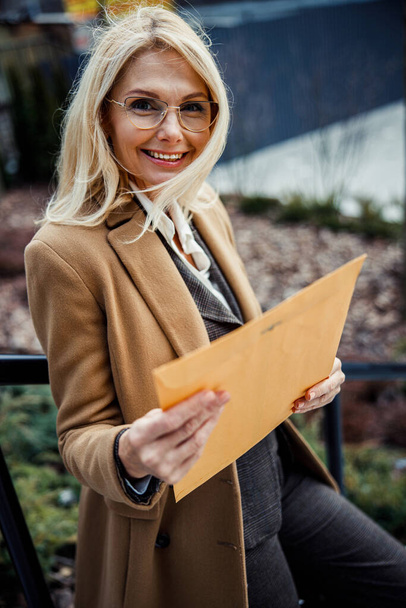Cheerful woman in eyeglasses holding an envelope - Fotó, kép