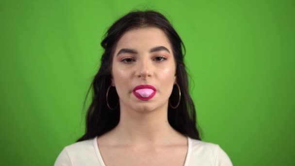 Usmívající se dívka foukání žvýkačka na zelené obrazovce žvýkání růžová bublina žvýkačka - Záběry, video