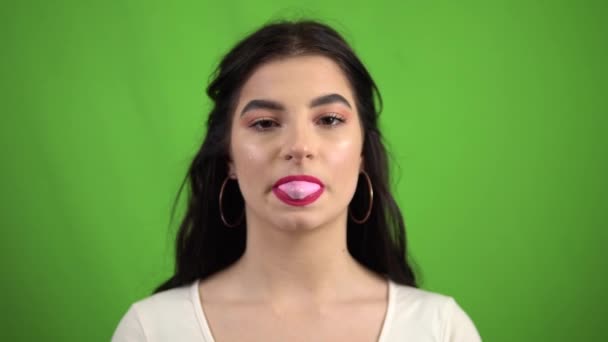 Joven chica sonriente sexy soplando goma de mascar en la pantalla verde
 - Metraje, vídeo