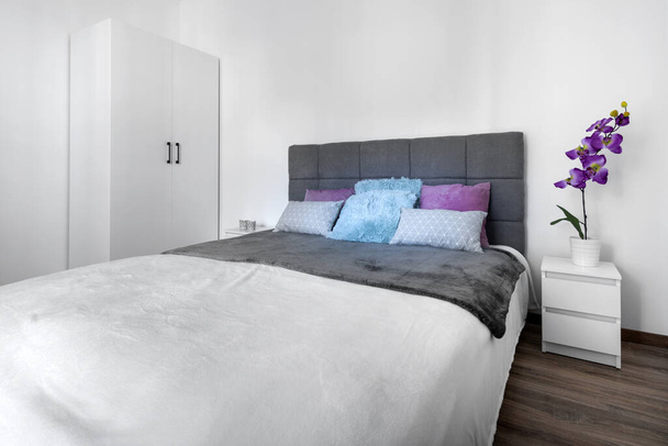 Diseño moderno dormitorio interior con cama acogedora gris
. - Foto, imagen