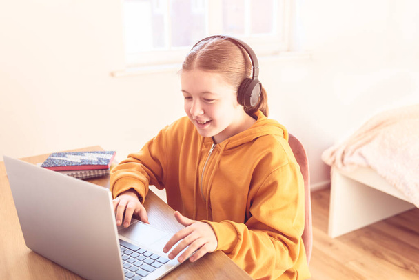 Kouluikäinen tyttö on kotona koulunkäyntiin kannettavan tietokoneen avulla aikana itsensä eristäminen hänen makuuhuoneessa, online-koulutus, kotitehtävät, etäopetus
 - Valokuva, kuva