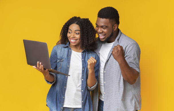 Glimlachende Afro-Amerikaanse paar kijken sport op laptop samen en juichen - Foto, afbeelding