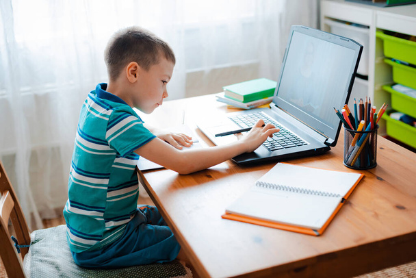 Etäopetus verkossa. Koulupoika opiskelee kotona ja tekee läksyjä. Kotona tapahtuva etäopetus - Valokuva, kuva
