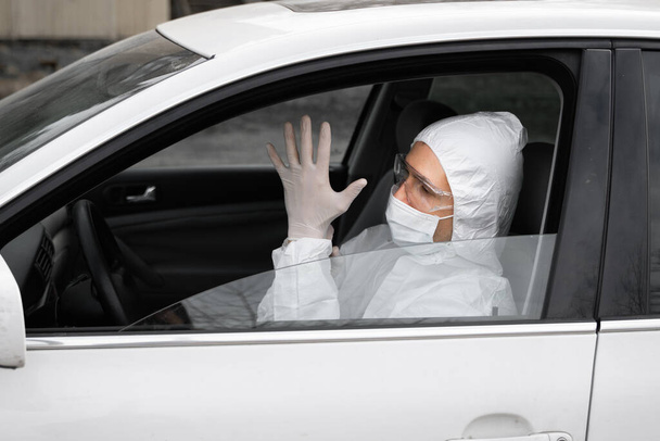 Man in protective suit, medical mask and rubber gloves for protect from bacteria and virus is planning to drive. Protective mask while quarantine, world pandemic, covid 19, coronavirus, infection. - Φωτογραφία, εικόνα