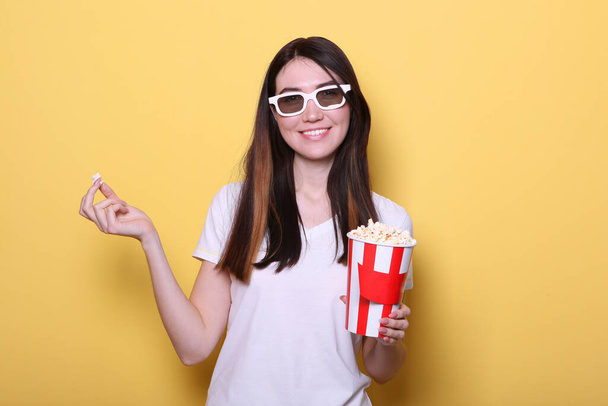 girl with popcorn on a colored background. Watch a movie, 3D movie. - Foto, Imagem