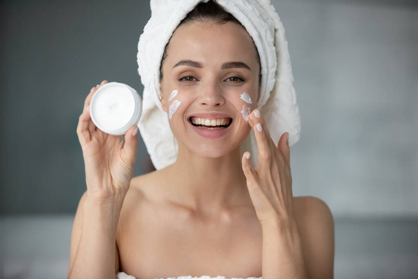 Smiling young female recommend moisturizing facial cream - Fotoğraf, Görsel