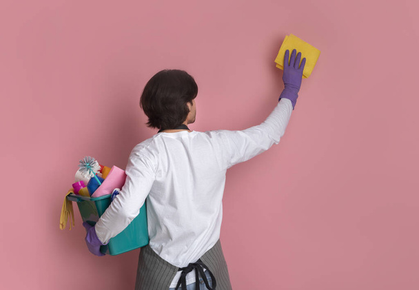 Úhledný muž čištění zdi s hadrem a drží vědro s pracími prostředky - Fotografie, Obrázek