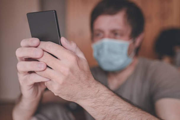 Беспокойный человек, использующий мобильный телефон в домашнем карантине самоизоляции для того, чтобы иметь Ковид-19 коронавируса симптомы, избирательный фокус
 - Фото, изображение