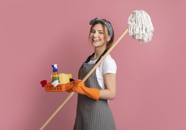 Limpeza profissional. Sorrindo jovem mulher com suprimentos domésticos em mãos
 - Foto, Imagem
