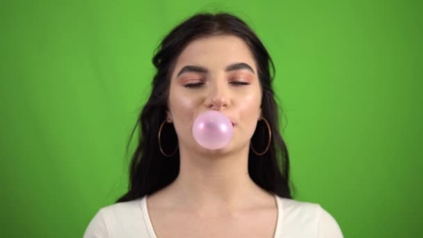 vicces mosolygós lány rágó rágógumi, fúj rózsaszín rágógumi zöld képernyőn - Felvétel, videó