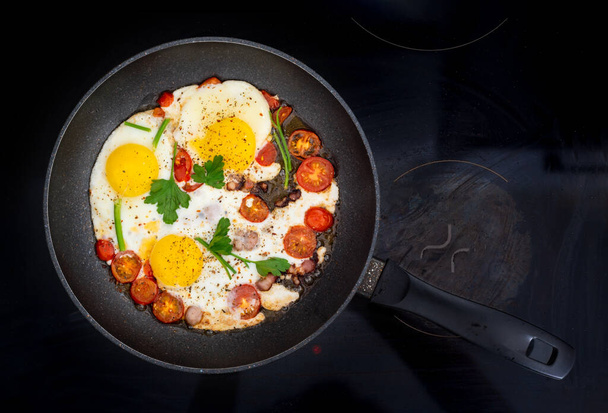 Жареные яйца домашнего приготовления с помидорами и беконом на сковороде
  - Фото, изображение