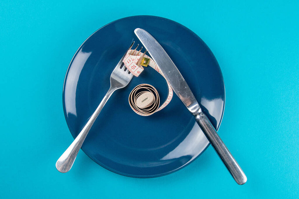 Measuring tape on a fork and knife - dieting concept image. Top views, close-up - Foto, Bild