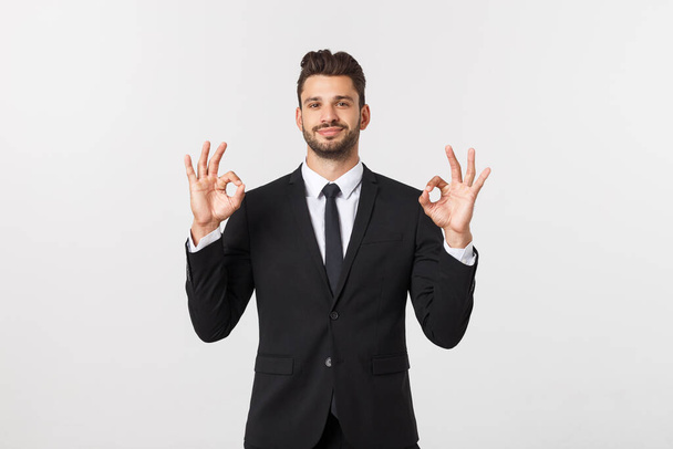 Handsome smiling businessman showing ok sign with fingers over gray background. - Фото, изображение