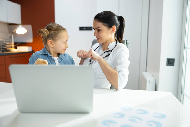 Nice young female pediatrician wants to become friends with her little patient - Photo, image
