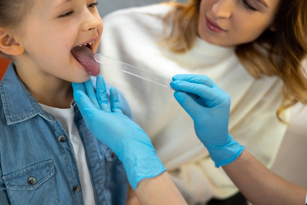 Cropped photo of pediatrician in rubber gloves examines little patient - Foto, afbeelding