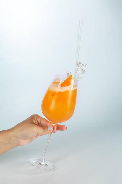 Close up of a hand holding a glass of Singapore cocktail on white background with copy space. - Foto, imagen